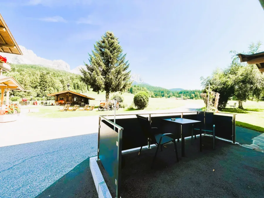 Terrasse mit Sitzplatz vor dem Doppelzimmer Parterre, dahinter Garten und Wilder Kaiser